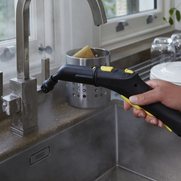 Hand using a portable steam cleaner to clean a kitchen faucet, demonstrating the device's application in a home environment.